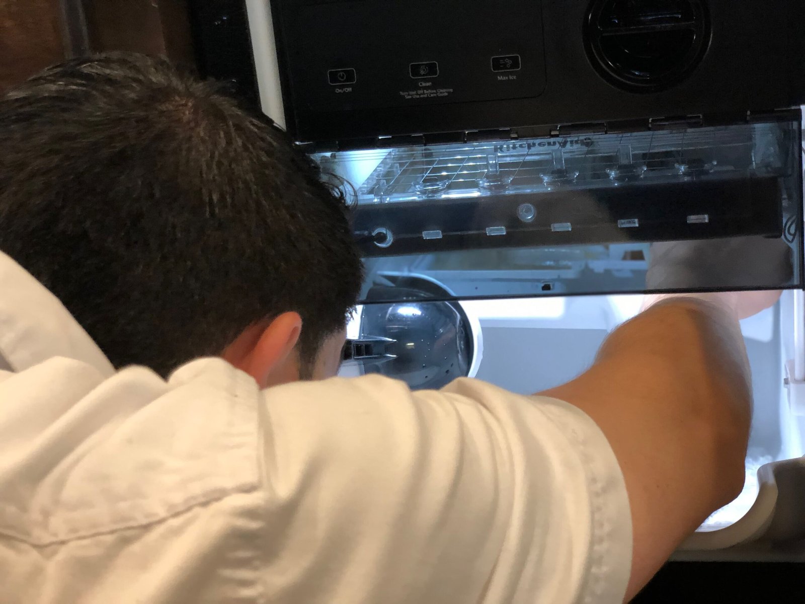 Professional appliance repair technician performing a detailed diagnostics of a refrigerator ice maker system.