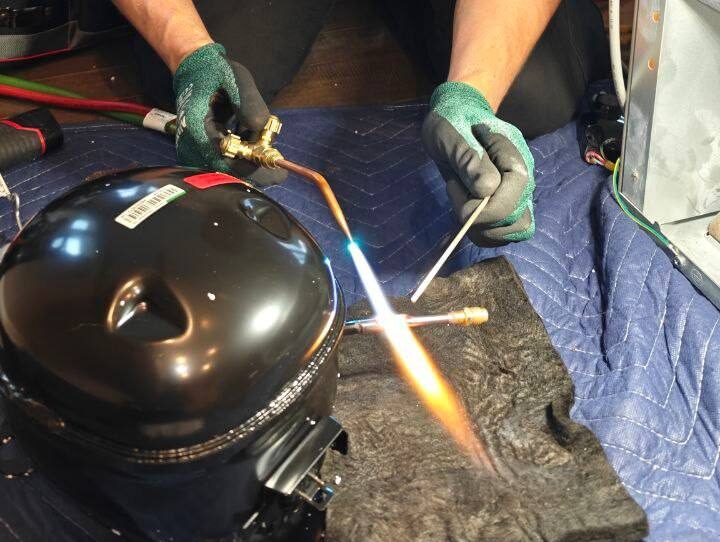 Professional technician performing a sealed system repair and compressor installation on a Sub-Zero refrigerator in a residential kitchen.