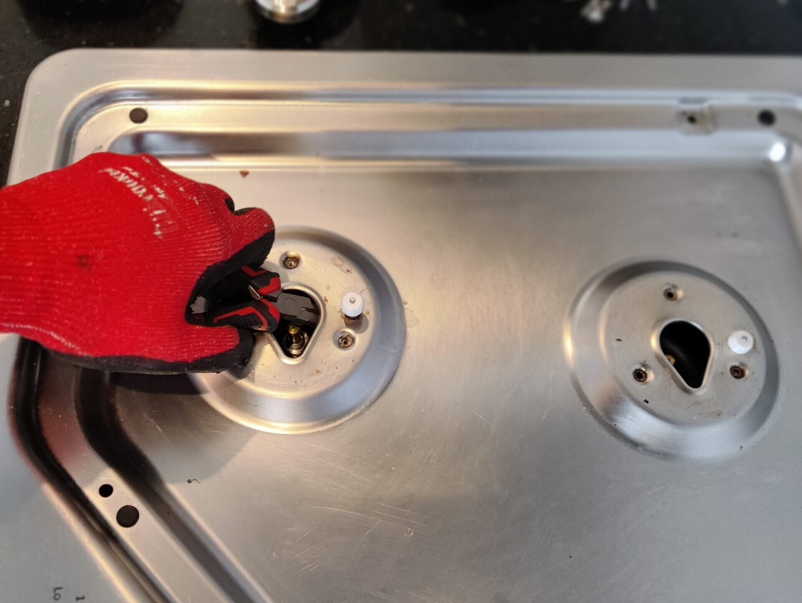 Technician performing maintenance and calibration on Wolf gas range burner ports for precise flame control.