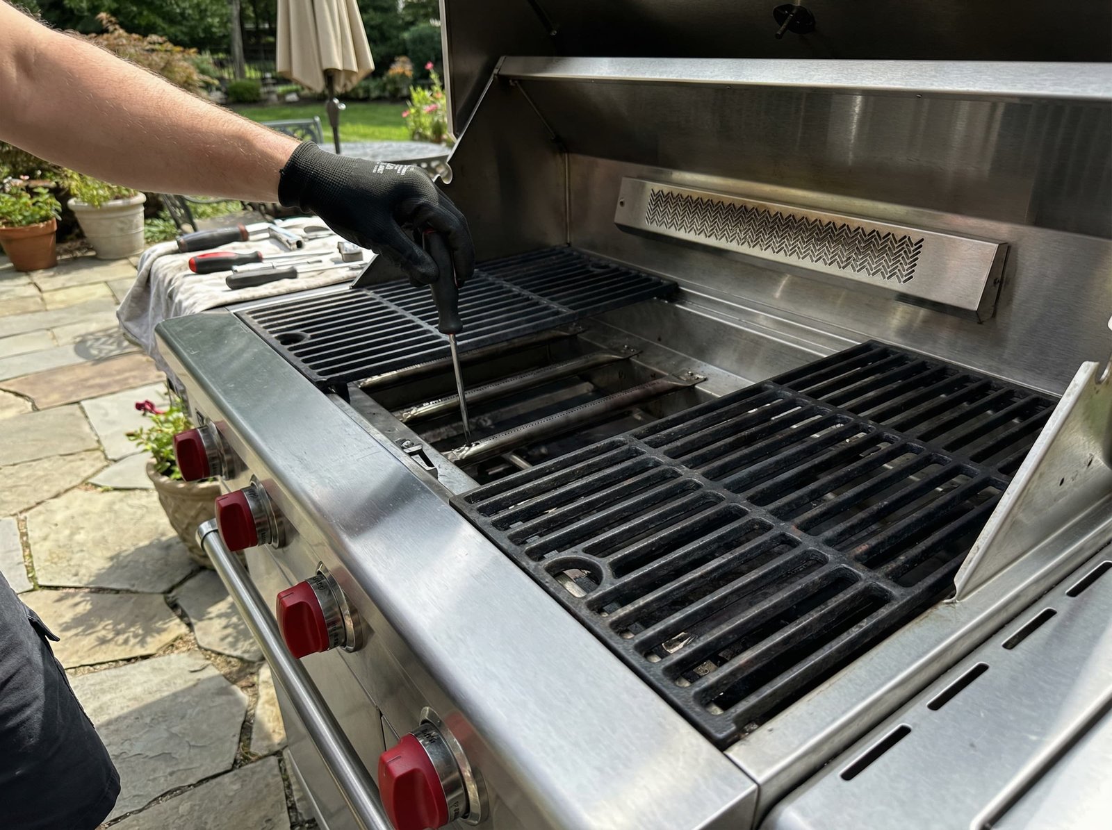 Professional appliance technician performing maintenance on a premium Wolf outdoor gas grill on a residential patio.